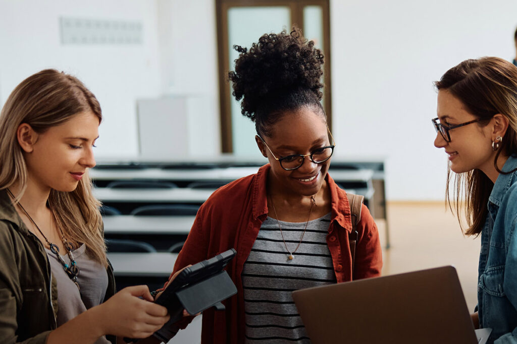 Three students talking to one another in a classroom
