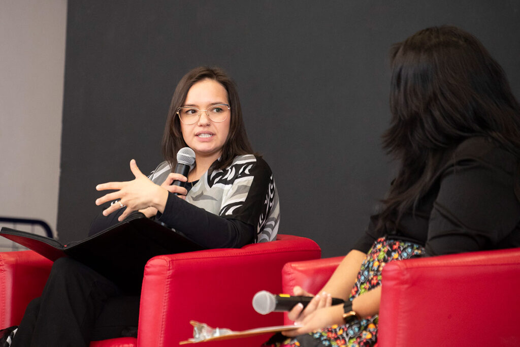 Two people sitting in chairs speaking on stage