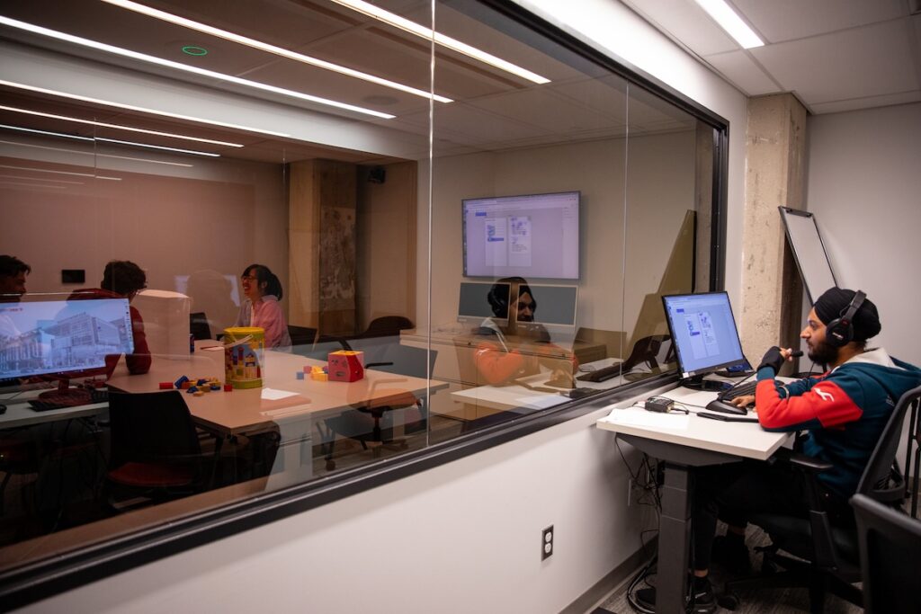 Student observing focus group interaction at a modern facility
