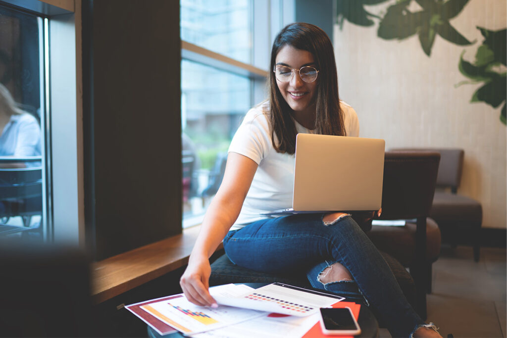 cheerful young woman working on diploma in college room