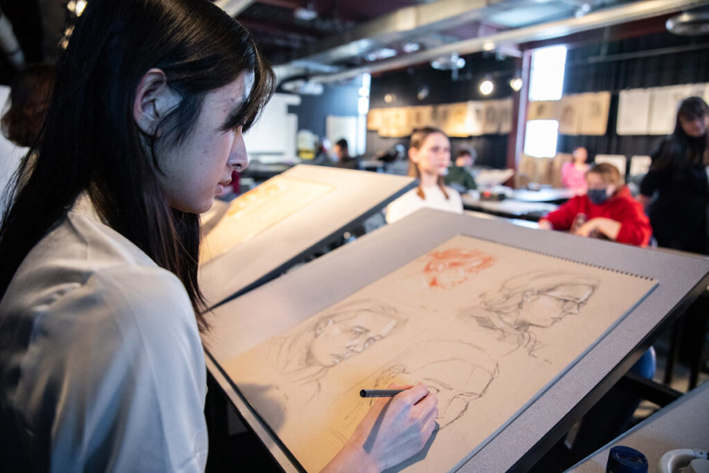 A graphic design student in a classroom at RRC Polytech working on an illustration project