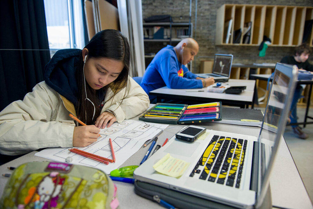 A graphic design student in a classroom at RRC Polytech working on an illustration project