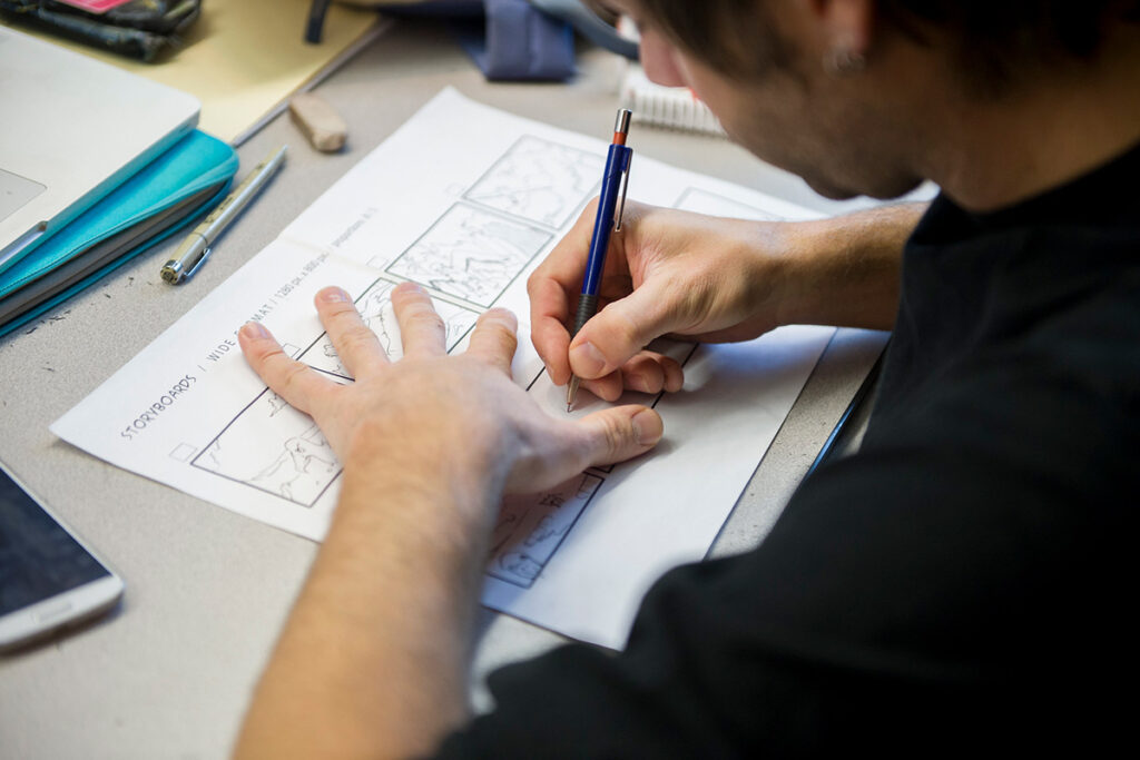 A graphic design student in a classroom at RRC Polytech sketching a storyboard