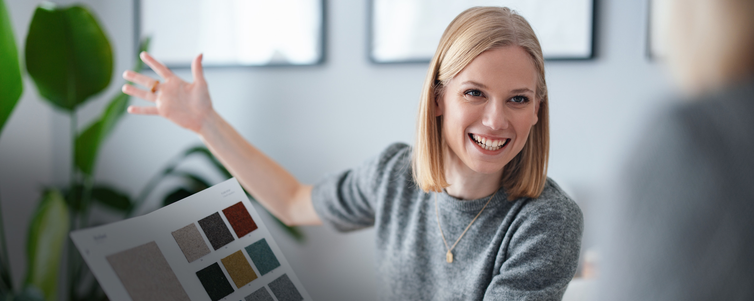 A smiling woman presenting a selection of color samples engaging in collaborative, creative decision-making for interior design or home improvement.