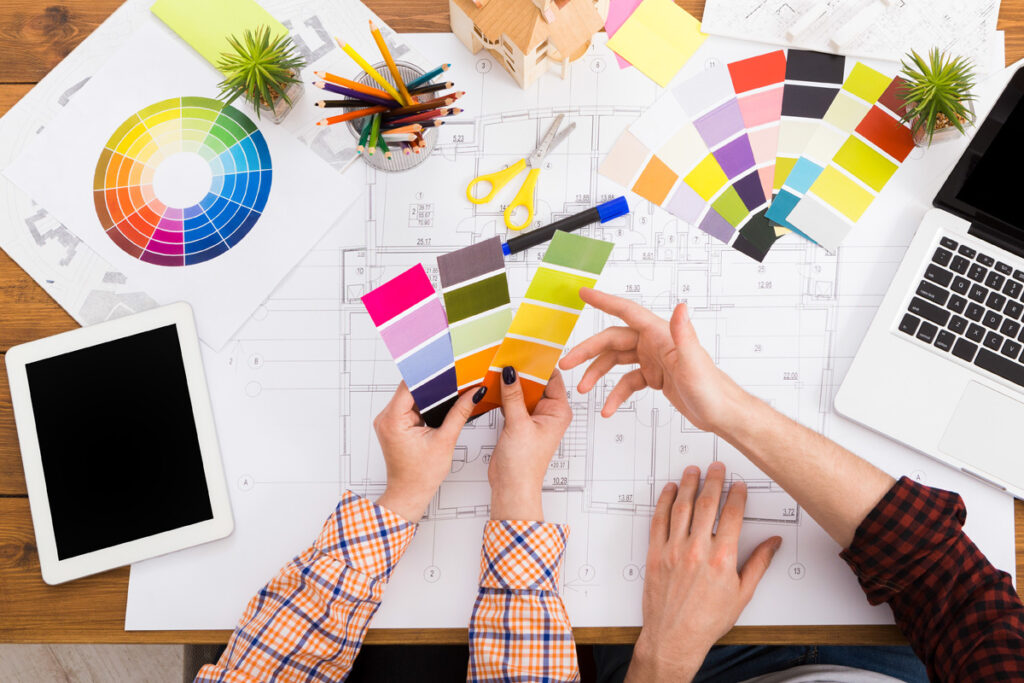 Interior designers teamwork with pantone swatch and house building plans on office desk, architects working with color palette, top view.