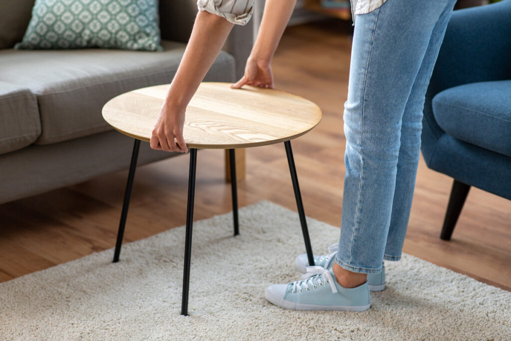 Close up of young woman placing coffee table next to sofa.