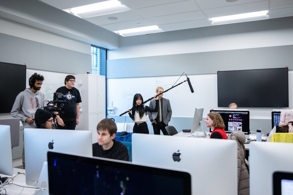 Behind-the-scenes view of a live entertainment production, with a student coordinating video equipment and stage lighting.