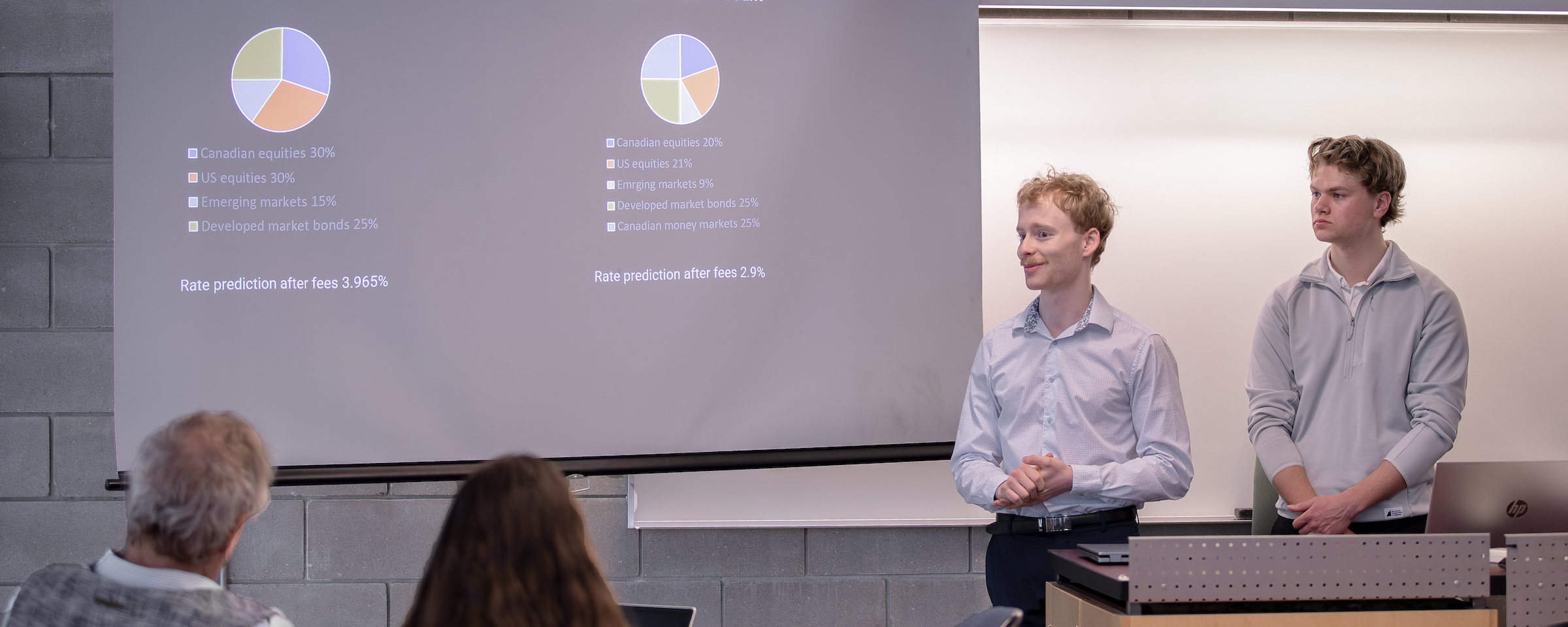 Two students delivering a financial presentation with pie charts showing investment portfolio allocations to an audience