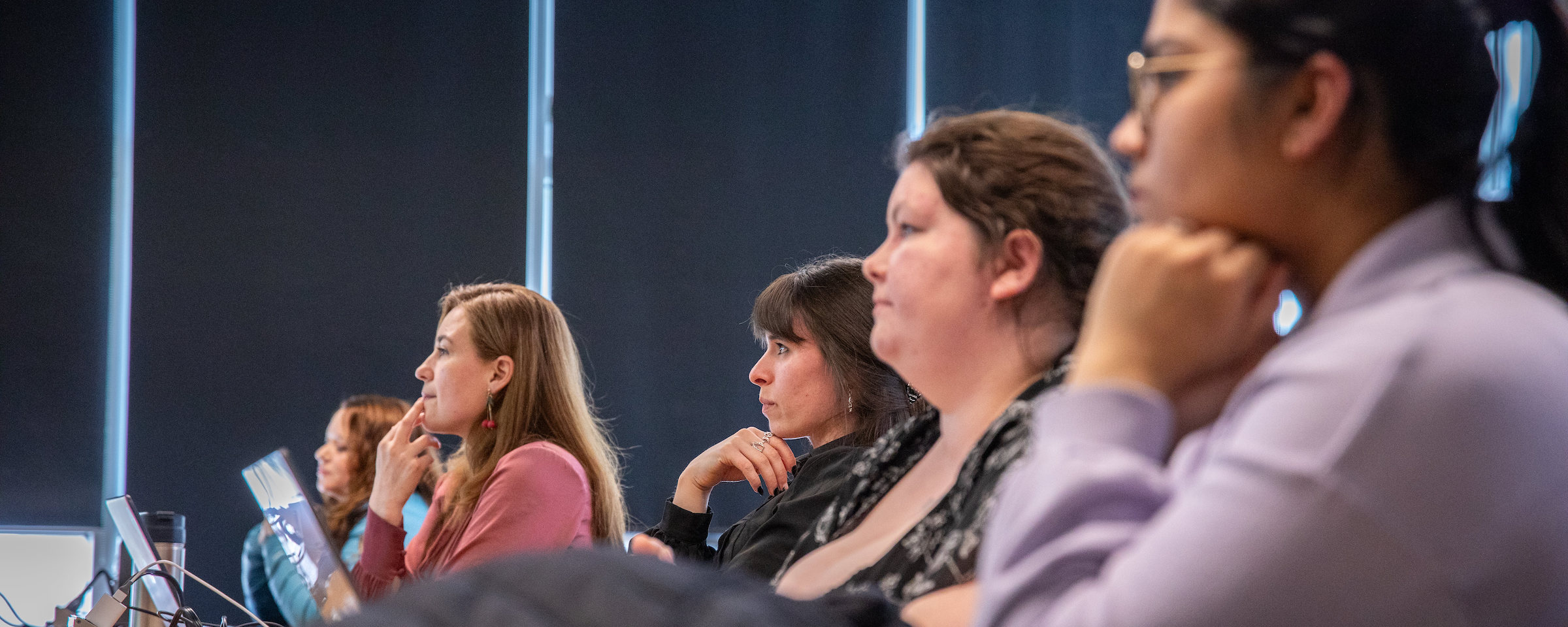 Students attentively listening during a panel discussion or workshop in a modern classroom setting