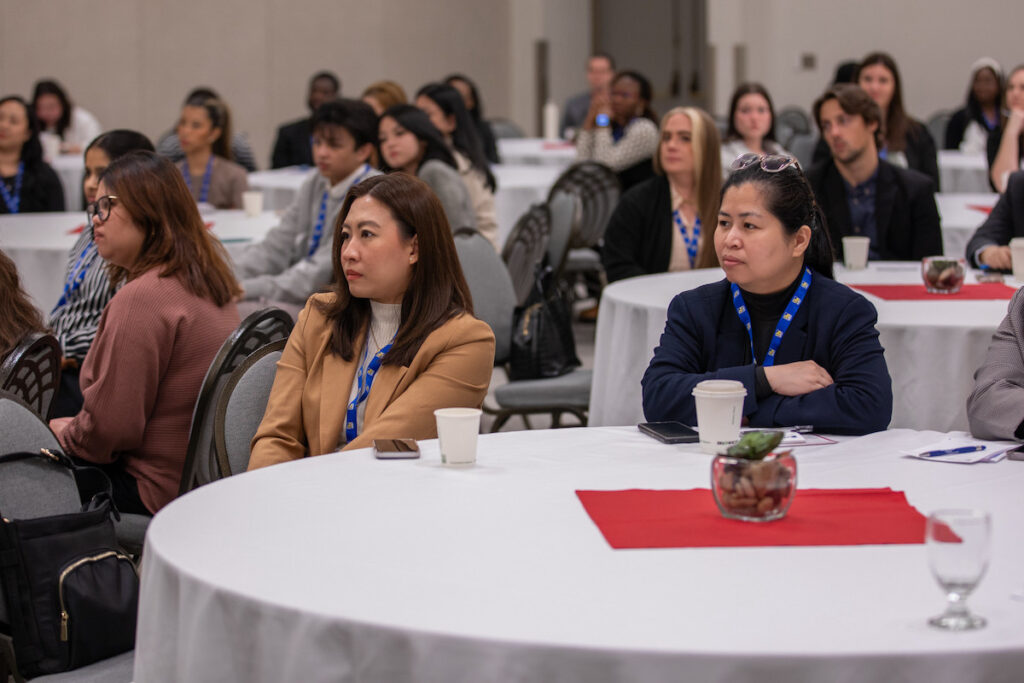 Attendees listening attentively during a presentation at a professional development event with round tables