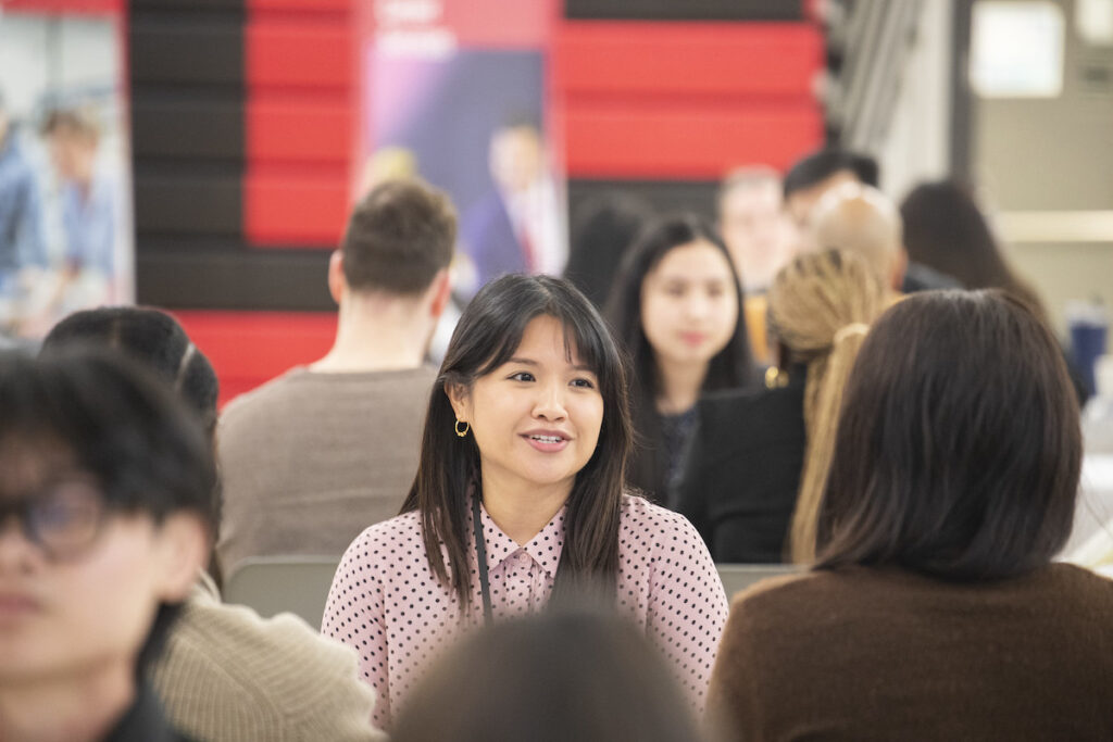 Student smiling while engaged in conversation at a networking or career event