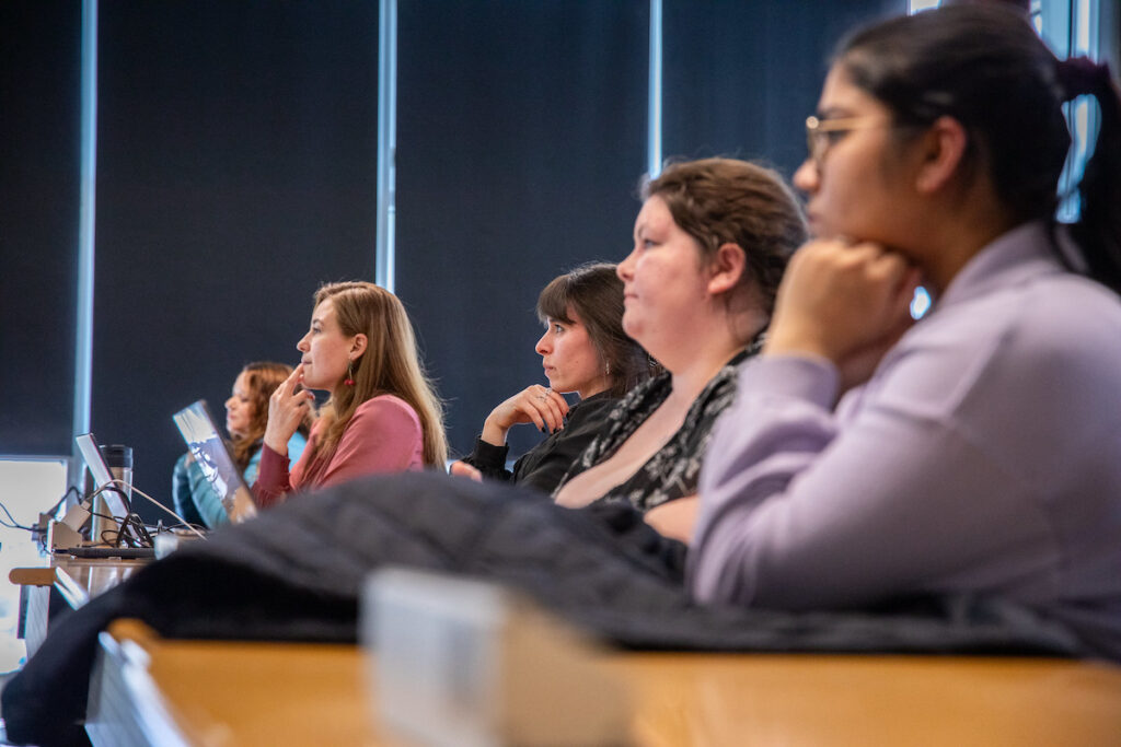 Students attentively listening during a panel discussion or workshop in a modern classroom setting