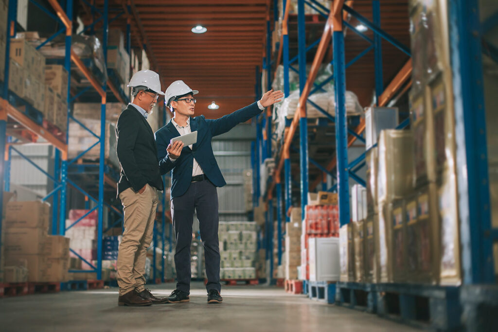 Two people wearing hardhats in a warehouse