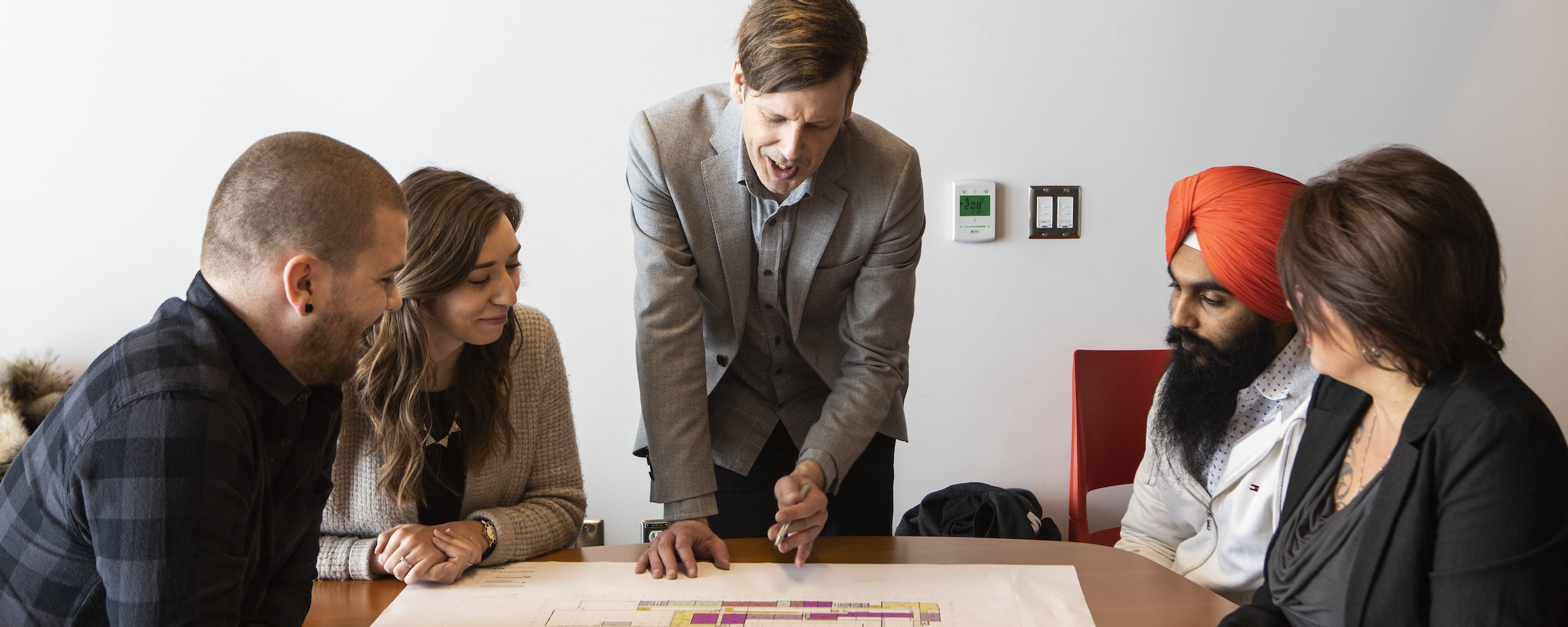 Students and instructor reviewing construction drafts at a roundtable