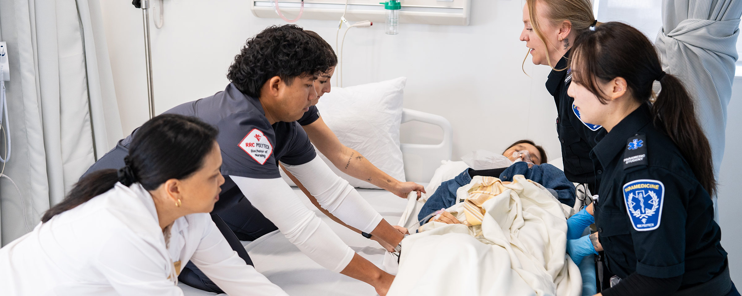 Nursing and paramedic students moving a person onto a hospital bed