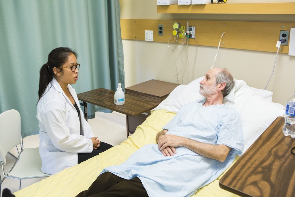 student interacting with a patient in a simulated hospital enviroment