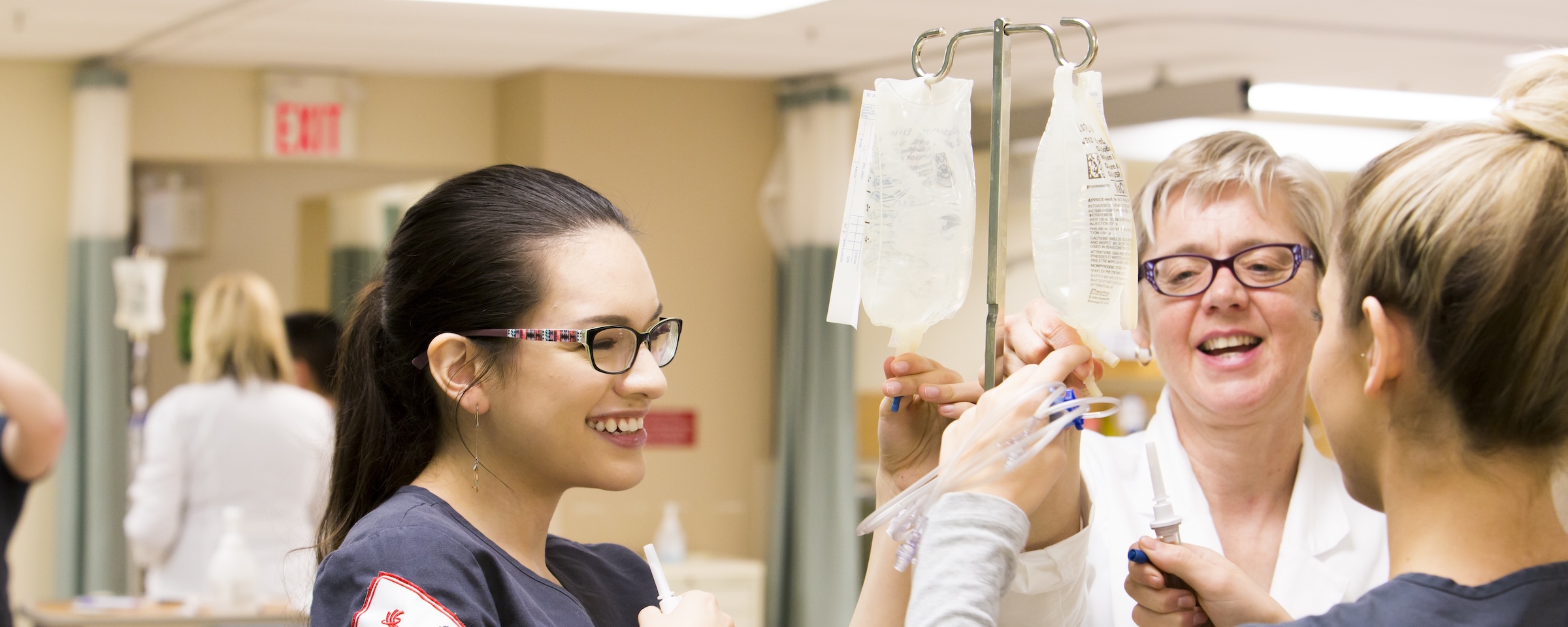 Nursing students practice intravenous therapy skills under instructor guidance in a clinical simulation lab.