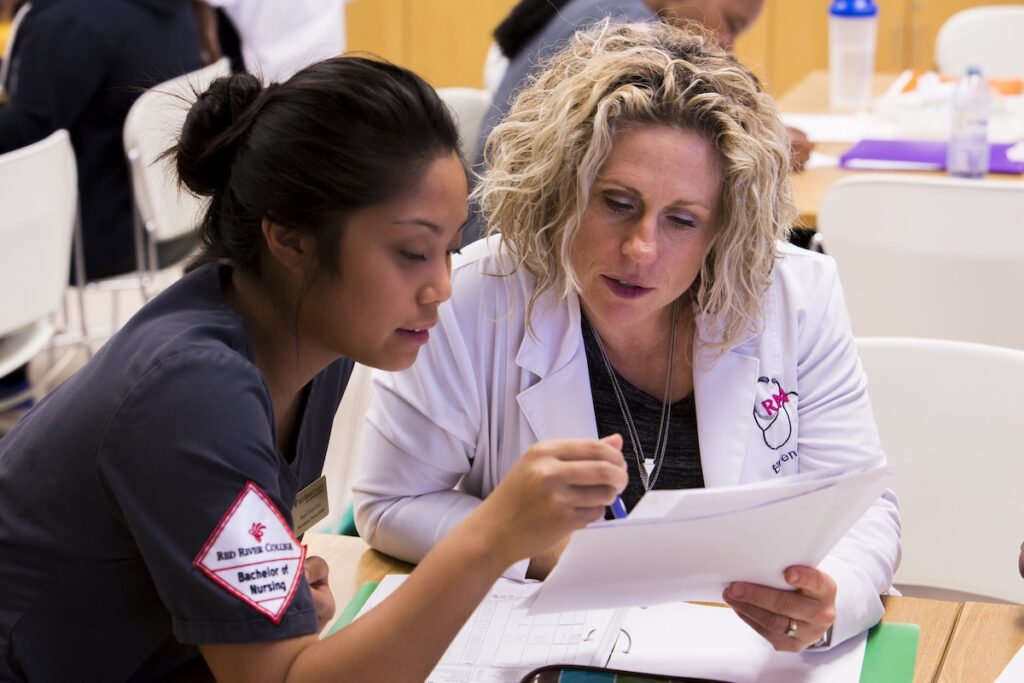 Instructor reviews patient documentation and assessment findings with a nursing student.