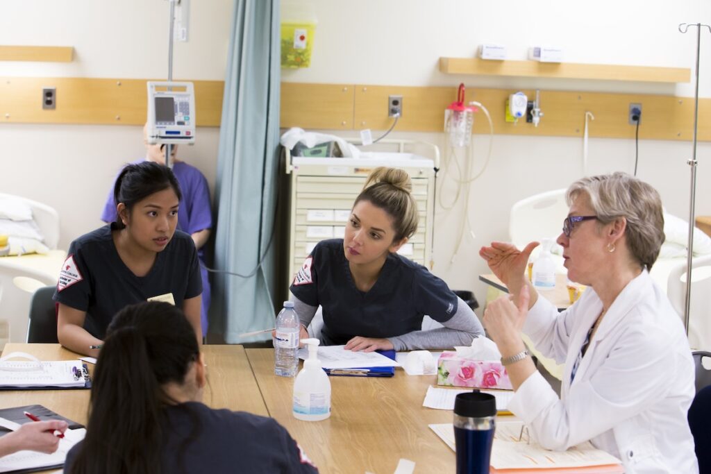 Instructor leads a discussion with nursing students during a clinical learning session.
