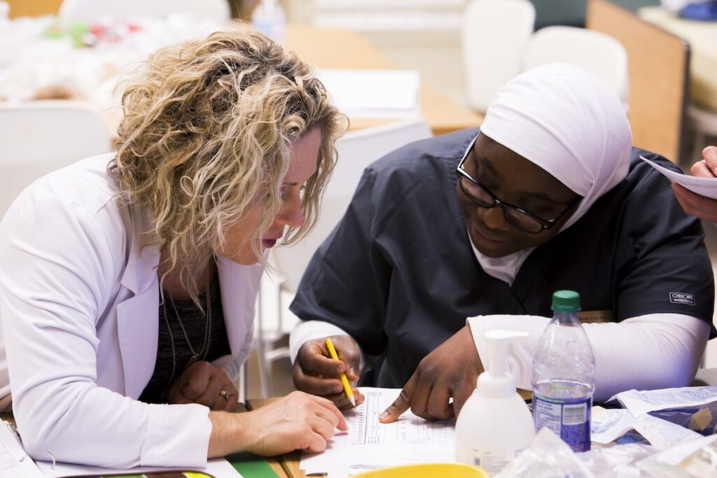 Instructor works with a nursing student to interpret clinical records and assessment data.