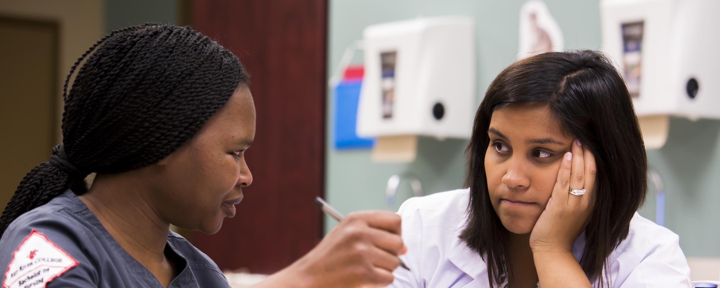 Nursing student and instructor discuss a patient care scenario during a clinical simulation exercise.