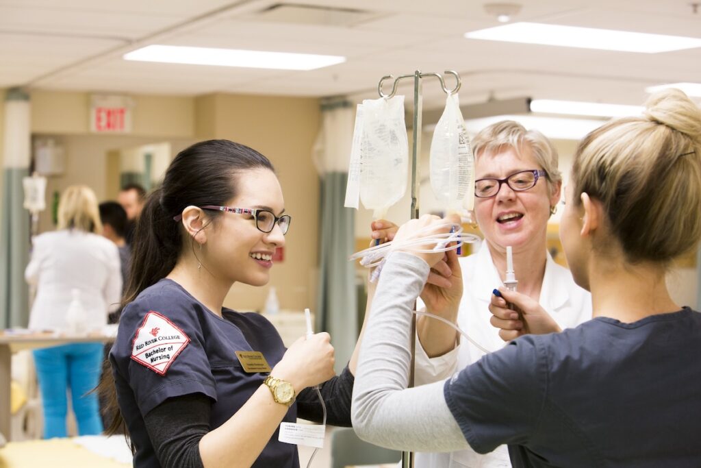 Instructor guides nursing students through intravenous therapy techniques in a simulation lab.