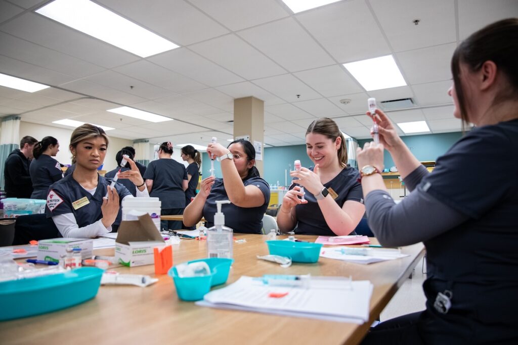 Nursing students prepare medication doses during a hands-on clinical skills lab.