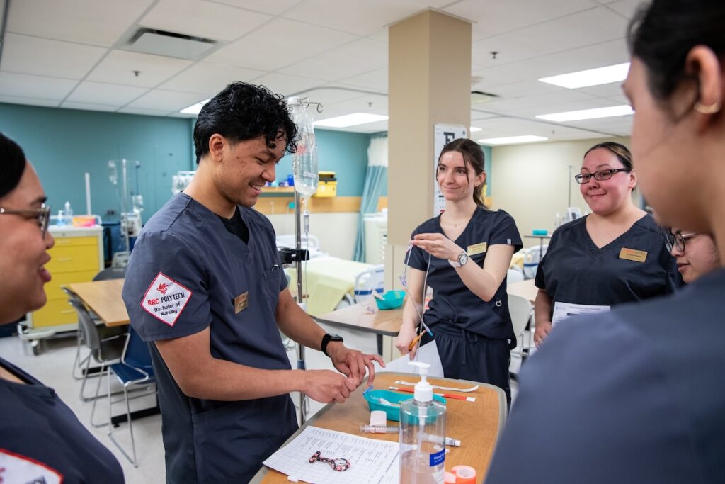 Nursing students participate in a clinical simulation exercise in a hospital-style training environment.