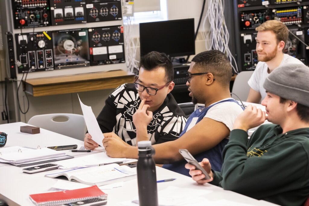 Engineering technology students review technical materials and work together on a classroom project.