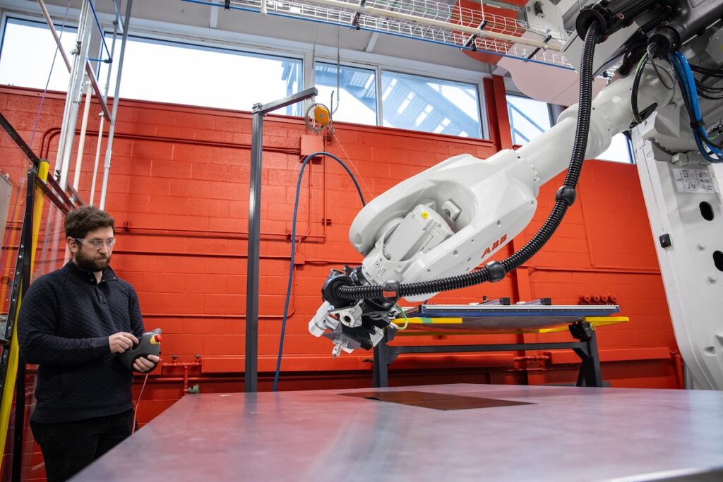 Graduate operates an industrial robotic system in an advanced manufacturing environment.