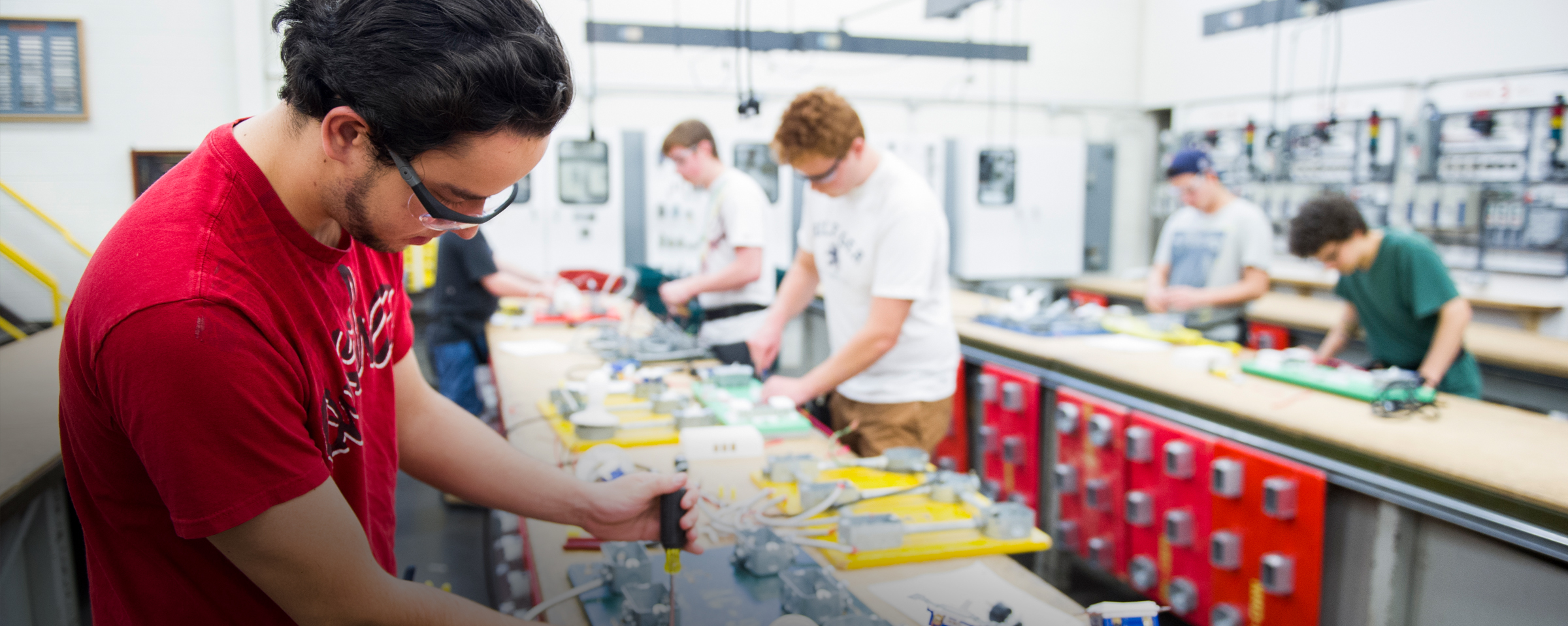 Students in an electrical lab working on a bench with electrical gear