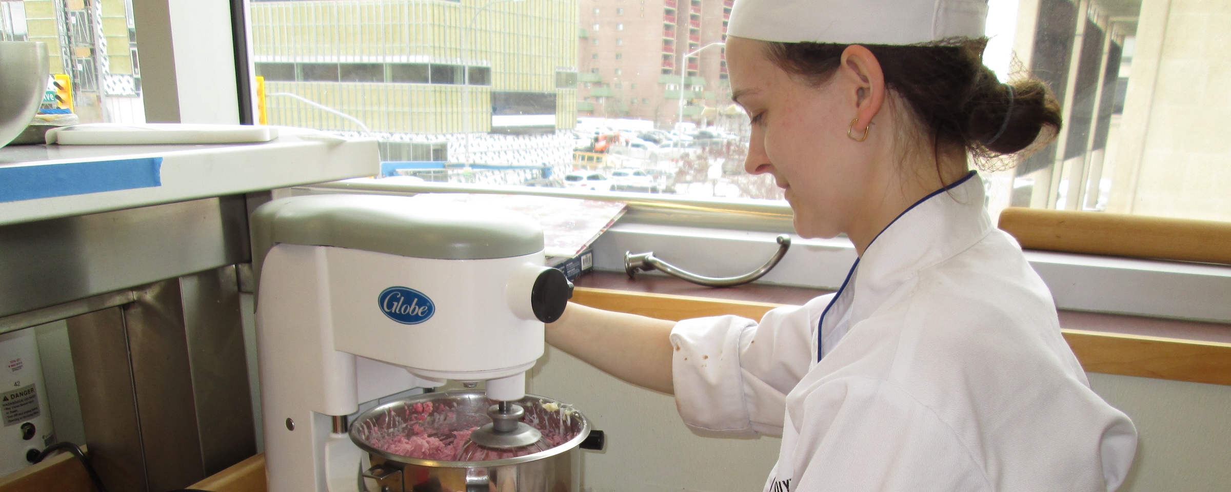 Baking and pastry arts student uses a commercial mixer in a teaching kitchen.