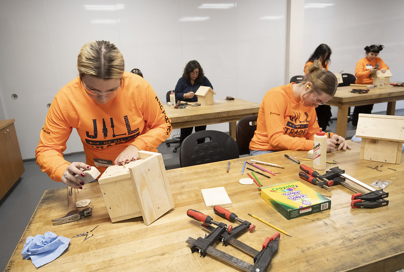 People build birdhouses in a carpentry lab.