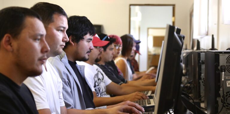 Students sit in front of computer screens in a classroom
