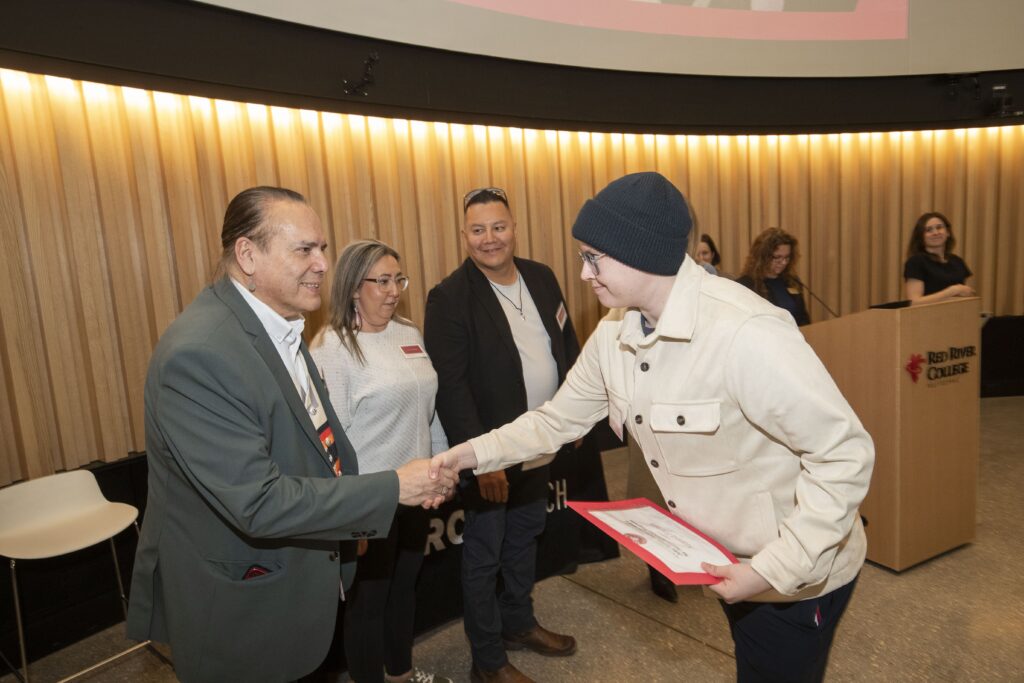 two people shaking hands at an awards ceremony