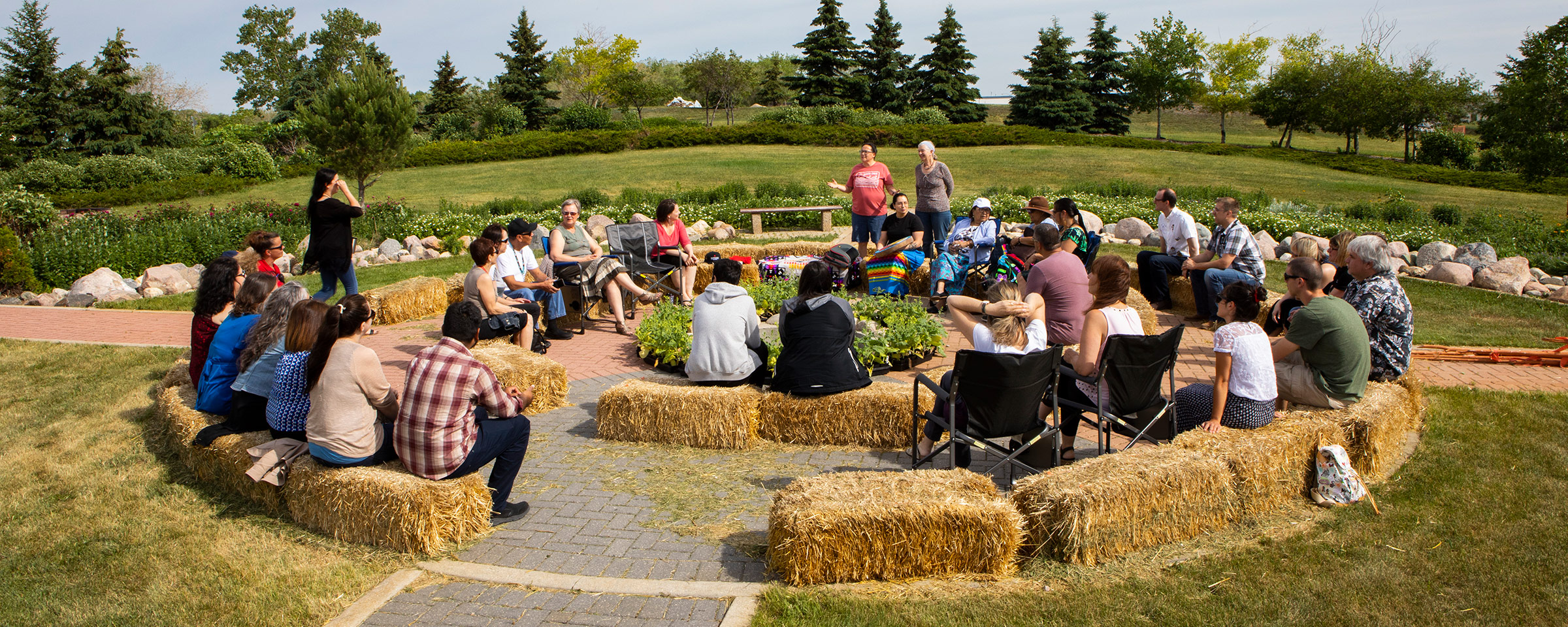 Group of people sitting in a circle sitting on hay bales