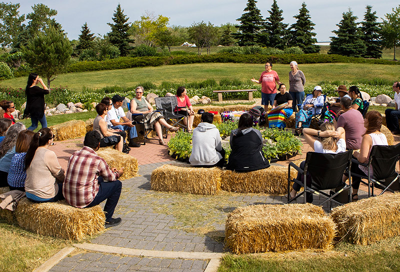 Group of people sitting in a circle sitting on hay bales