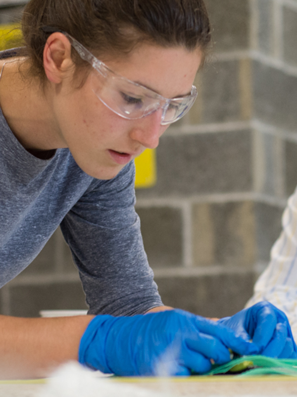 female with safety glasses and blue gloves on