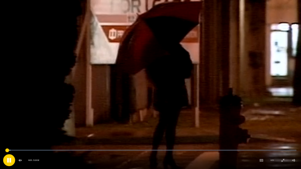 screenshot of the NFB films, showing a woman holding an umbrella standing on the street side