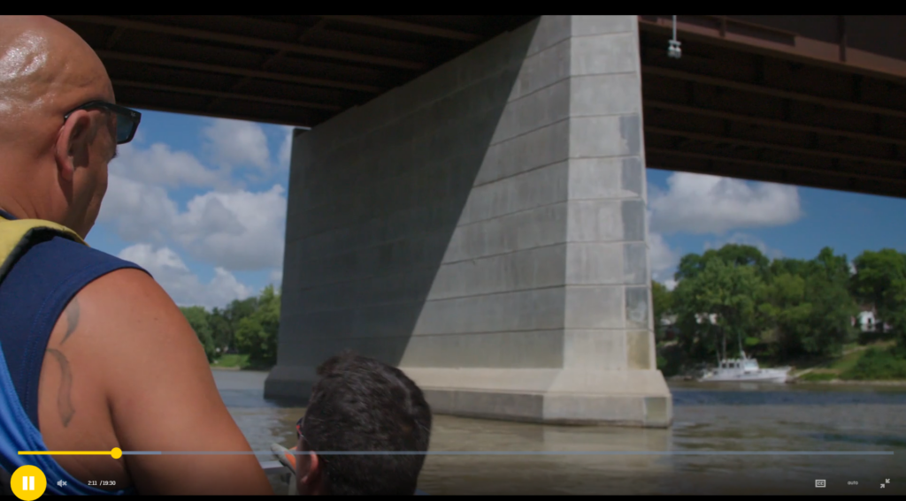 screenshot of the NFB film, showing an indigneous man riding a boat on the Red River