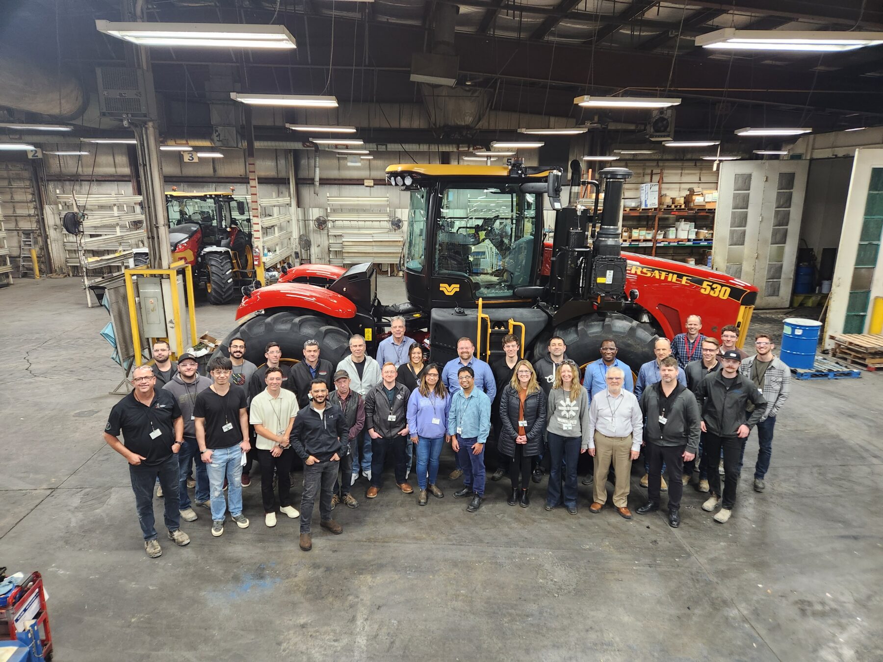 a group of people standing in front of a large piece of farm machinery