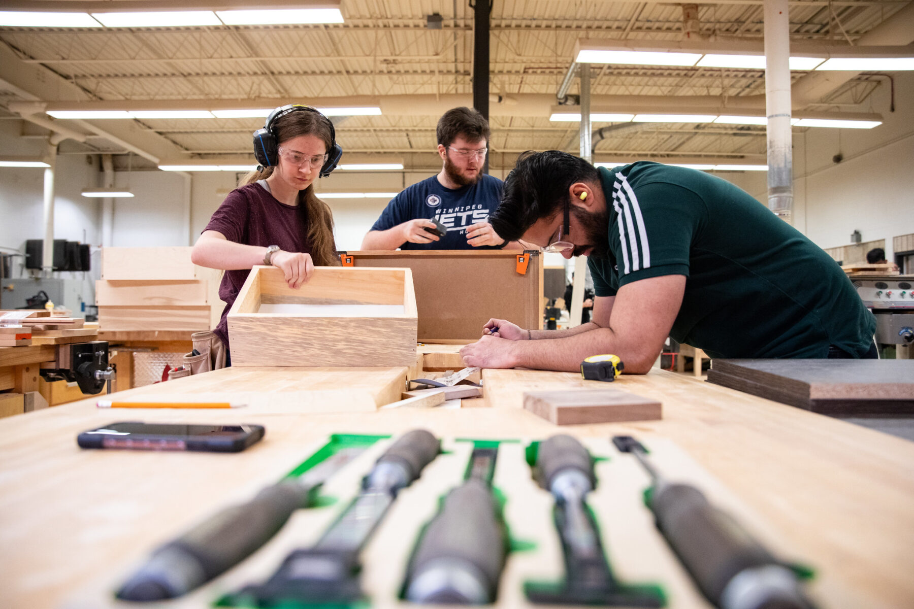 three students working collaboratively in the cabinetry and woodworking program