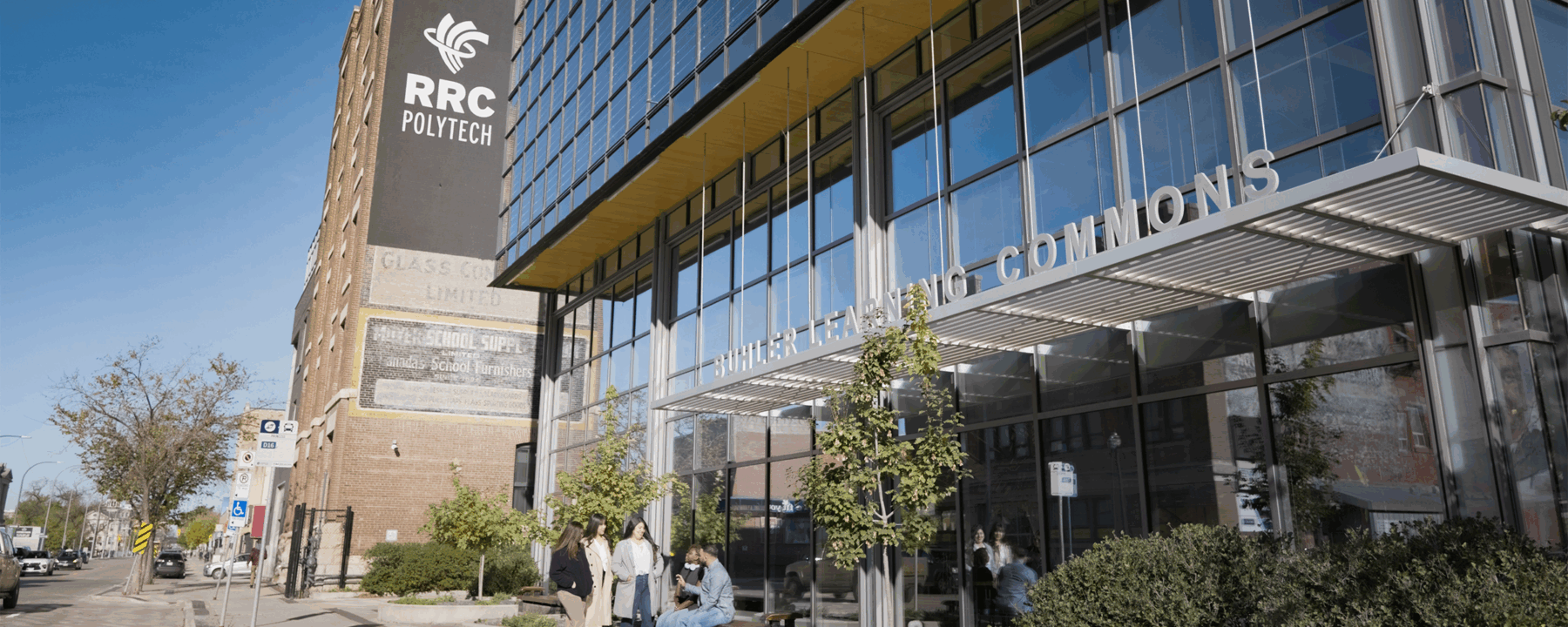 Five people in a circle chatting outside the William Ave entrance of RRC Polytech