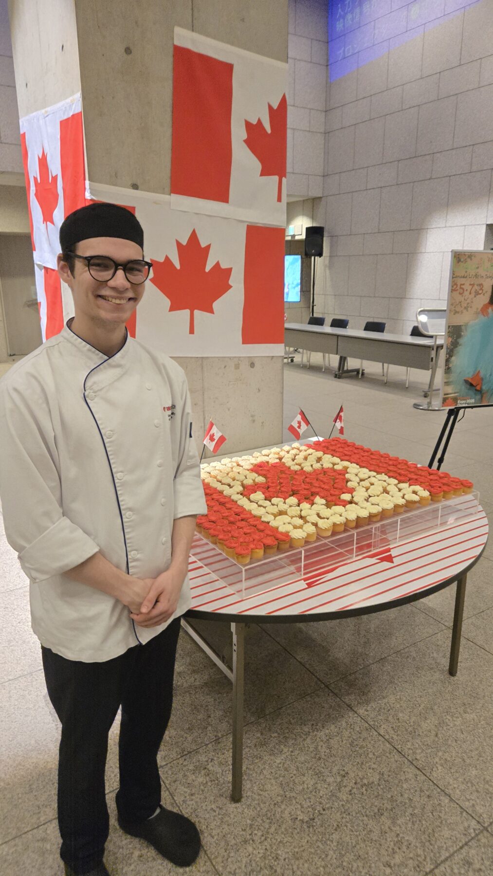 Chef posing with cupcakes that form a Canadian flag