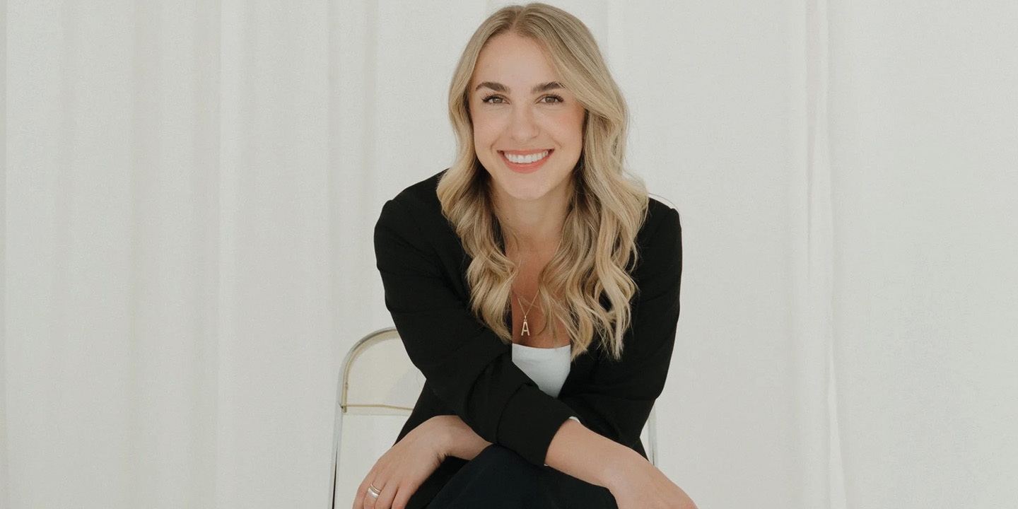 A woman is sitting on a chair, she is looking at the camera and smiling