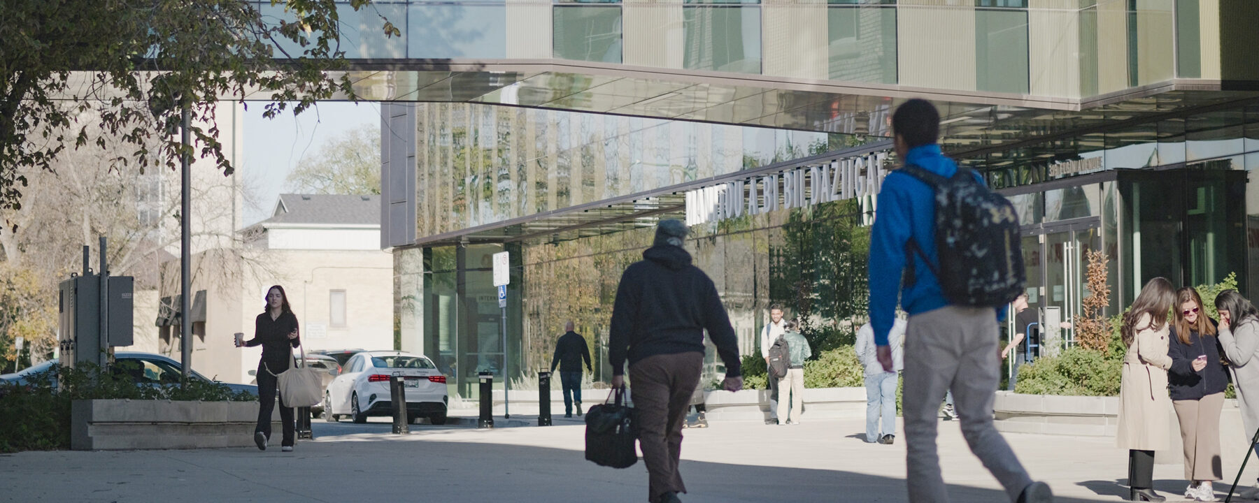 People walking outside near a modern glass building
