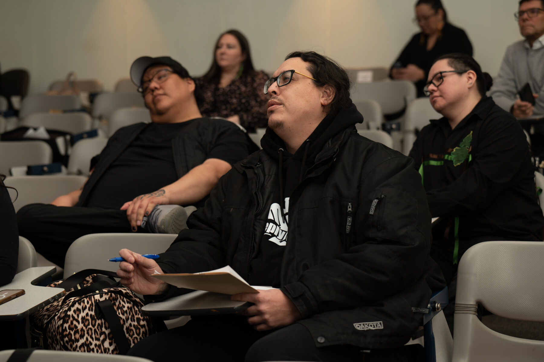 a judge holding a pad and paper among the audience at a pitch competition