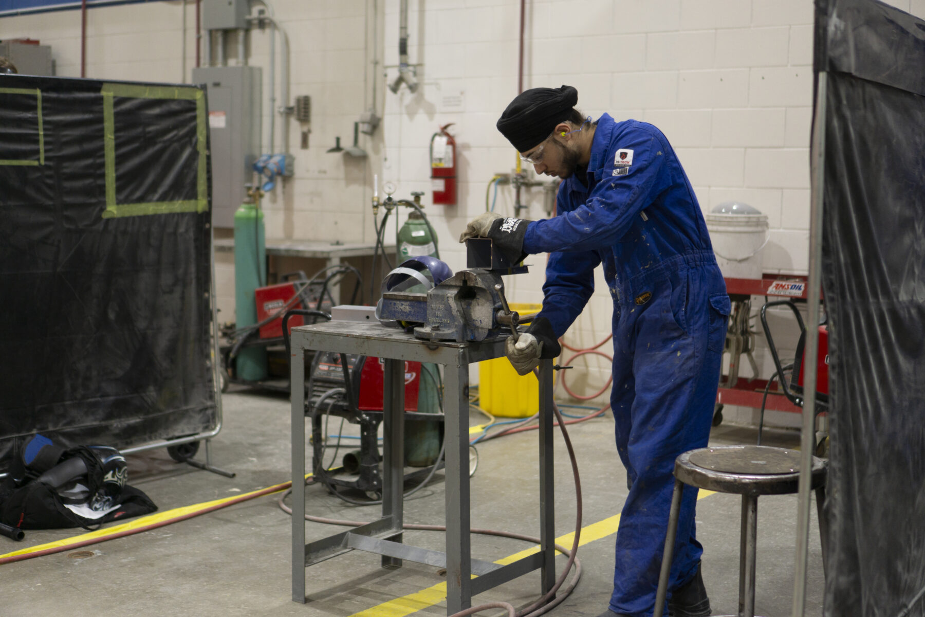 a person in overalls working in a mechanics lab