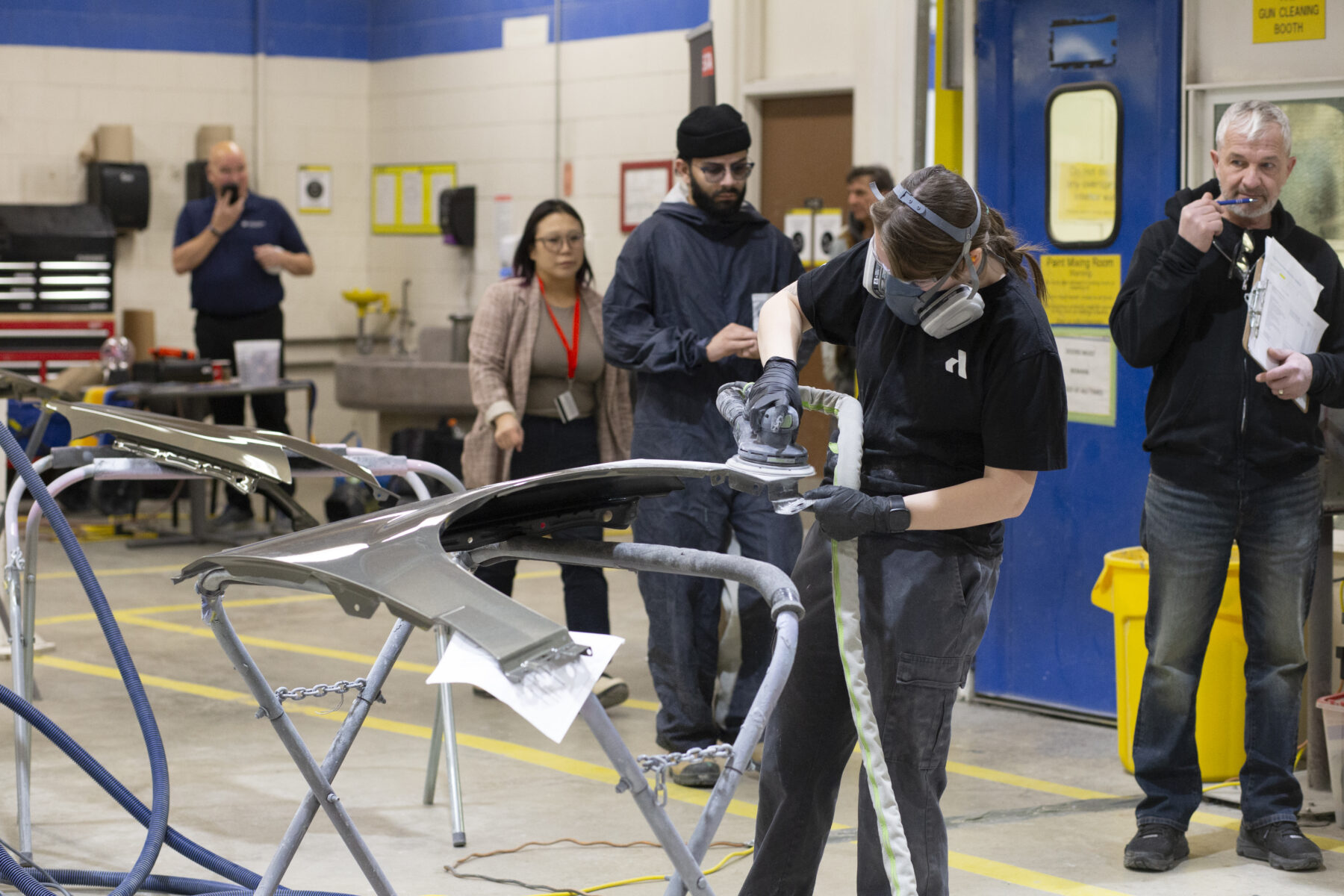 a person prepares a car panel for painting