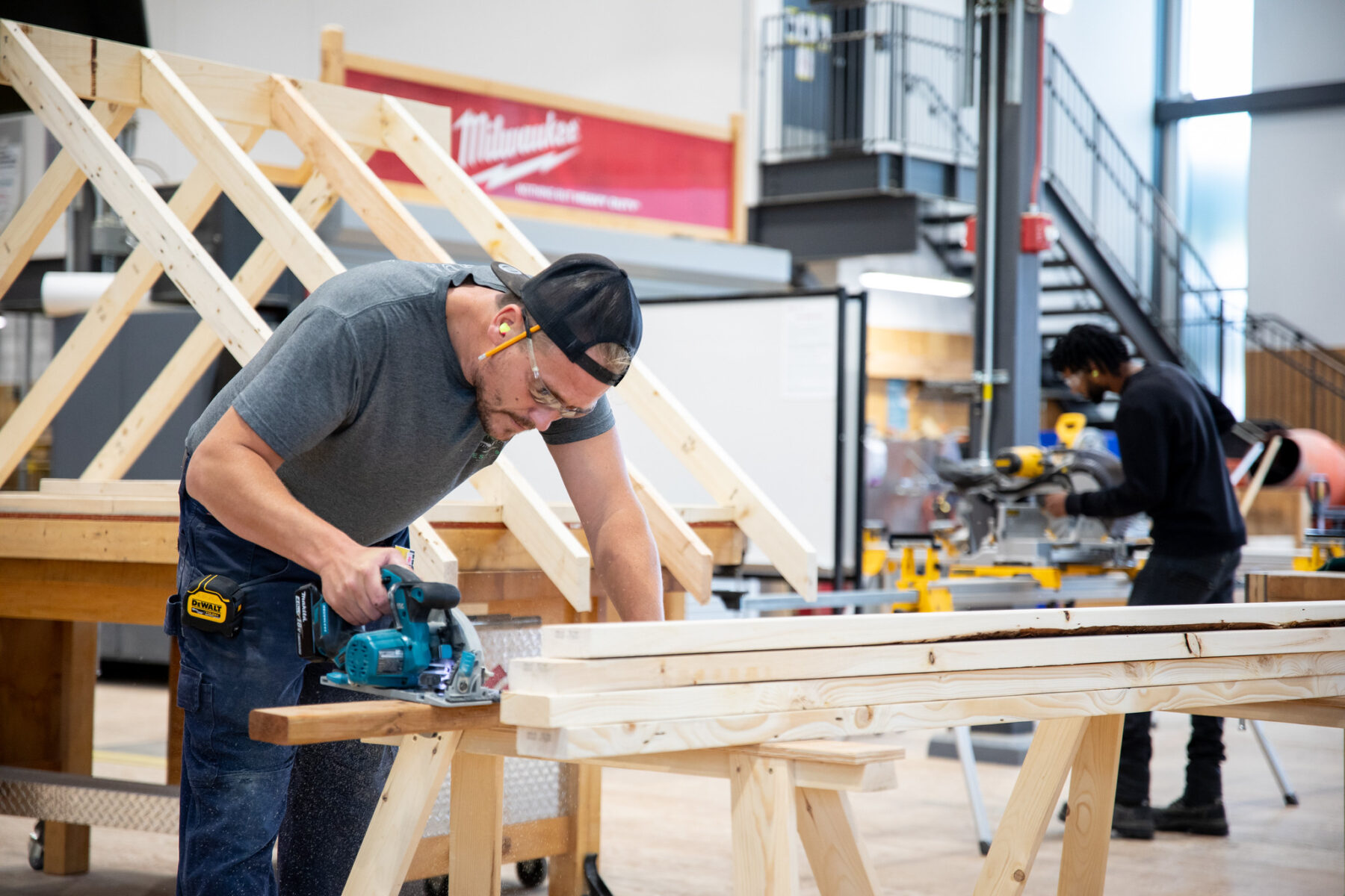 A man is using a saw to cut some wood in RRC Polytech's construction lab.
